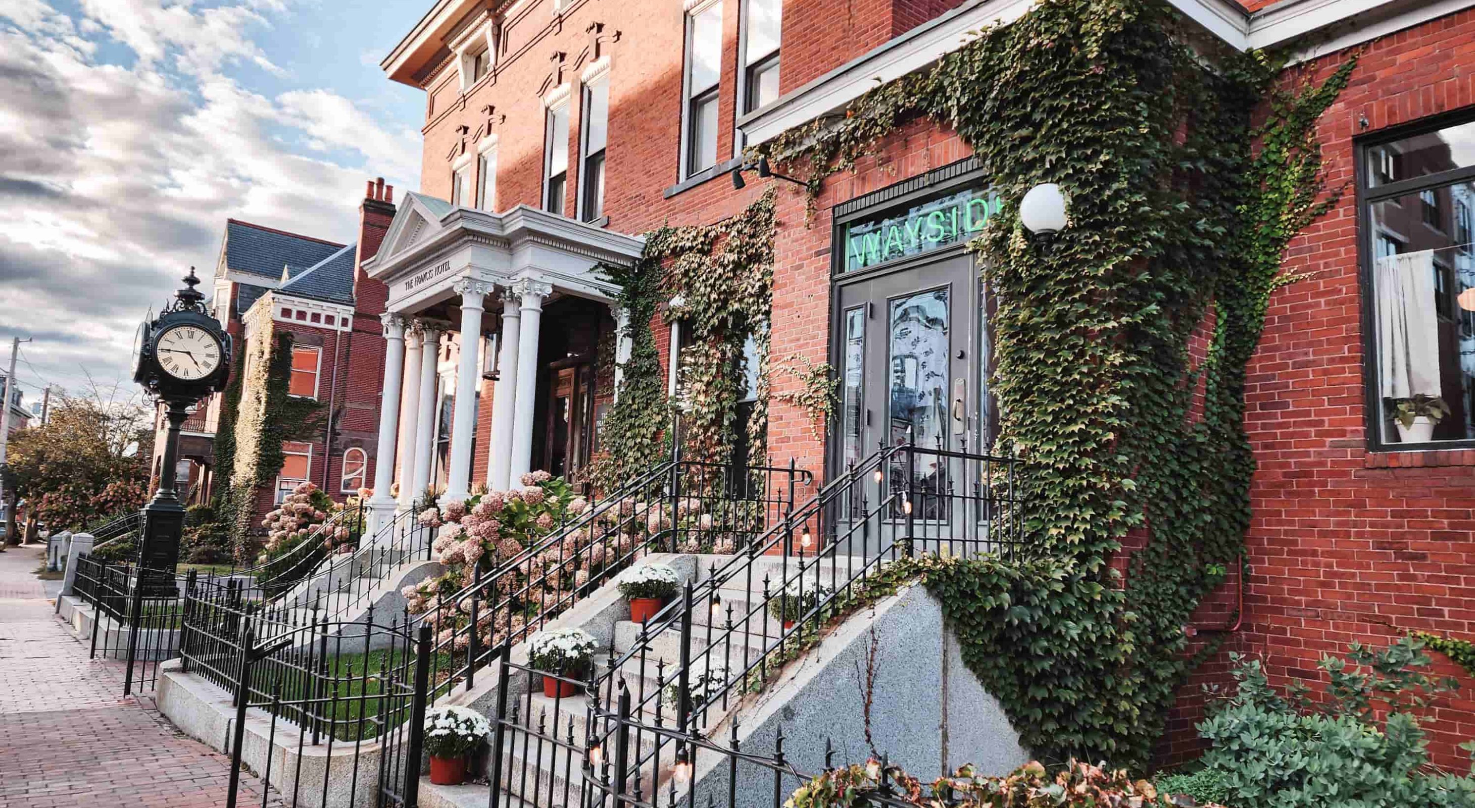 Historic brick hotel with ivy, surrounded by a charming street. Luxurious boutique escape.