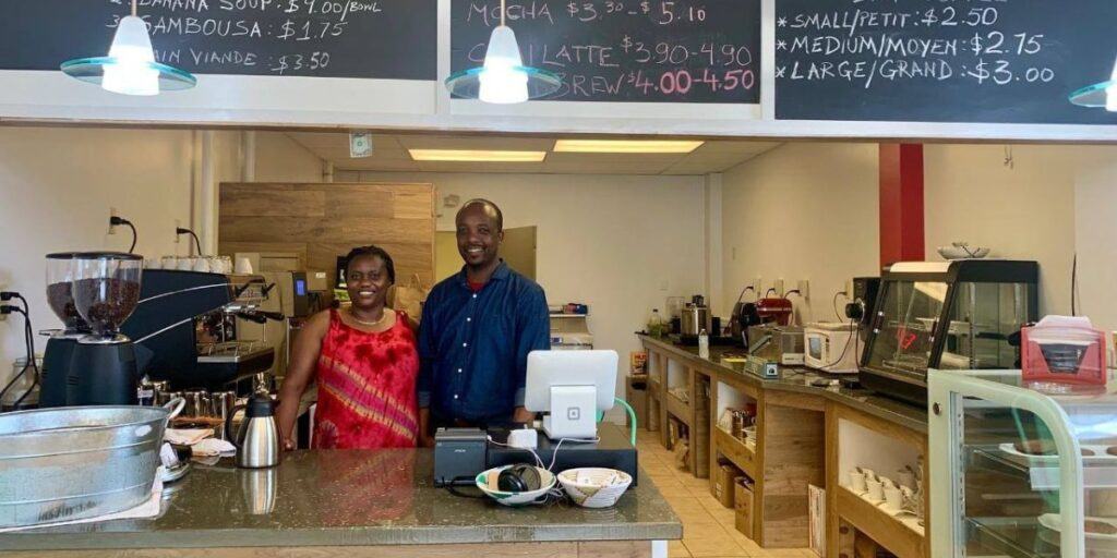 Friendly cafe owners smile behind the counter at a cozy coffee shop in Portland Maine.