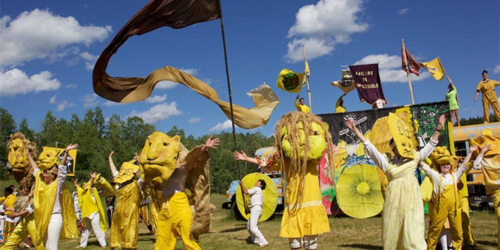 Colorful parade with yellow costumes and flags in a vibrant outdoor festival setting.