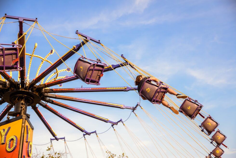 Enjoying a thrilling swing ride under clear skies, perfect for a Portland Maine getaway.