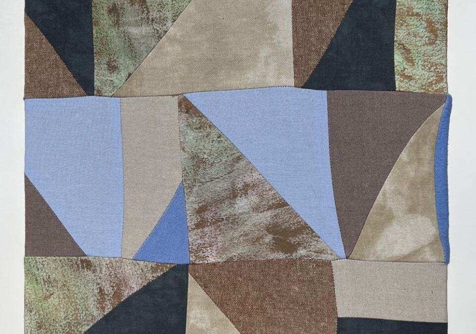 quilt with abstract geometric pattern with earthy tones and light blue accents.
